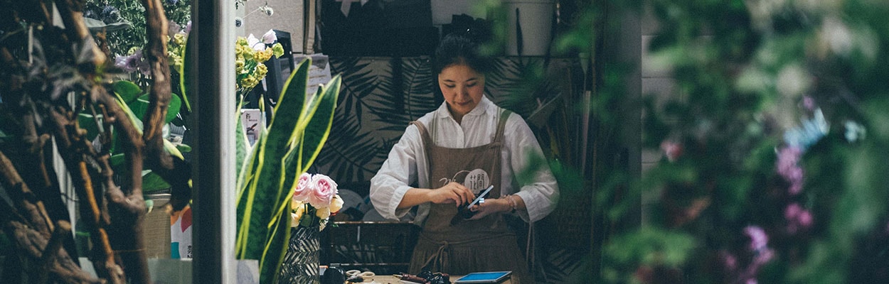 Photo of a business owner in their floristry shop, curating a bunch of flowers.